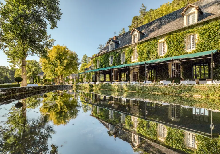 The exterior ivy-covered stone facade of Manoir d'Hautegente hotel in Coly-Saint-Amand, Dordogne.