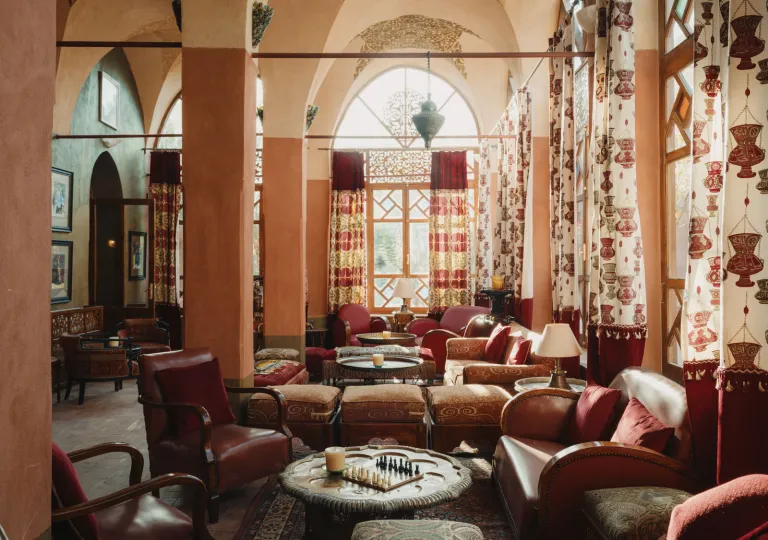 The Eastern Bar lounge inside the Al Moudira Hotel located on the West Bank of the Nile in Luxor, Egypt features traditional architecture with high vaulted arches and hand-painted murals.