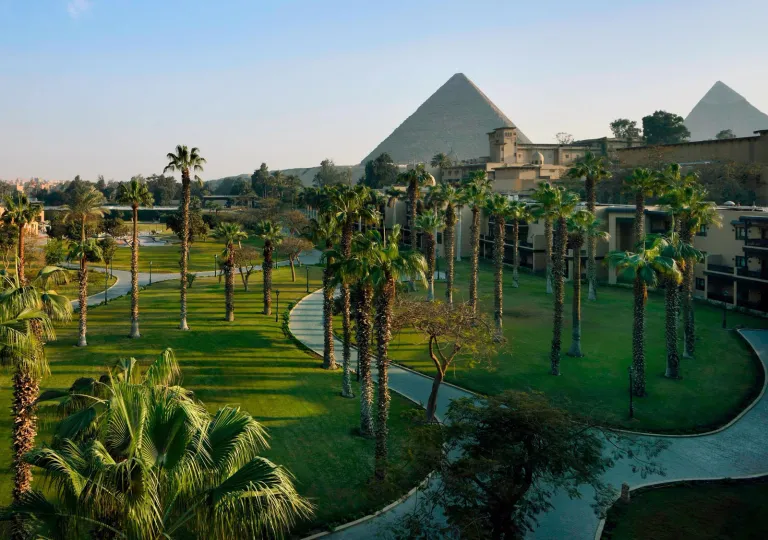 Palm tree-lined paths meander through the expansive garden wing with lush landscaped grounds at the Marriott Mena House, Cairo, located right at the base of the Giza Plateau.