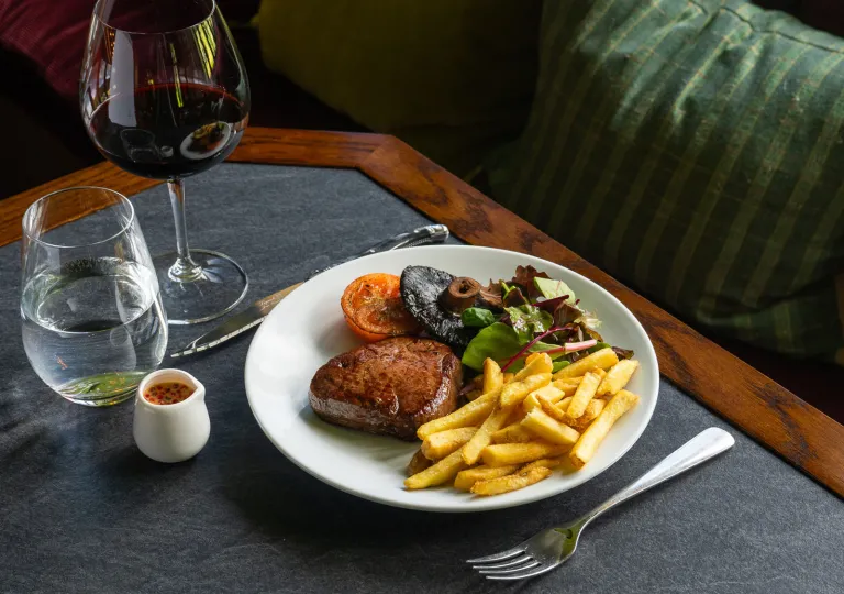 Plate of food with a fork and knife on either side, and a wine glass