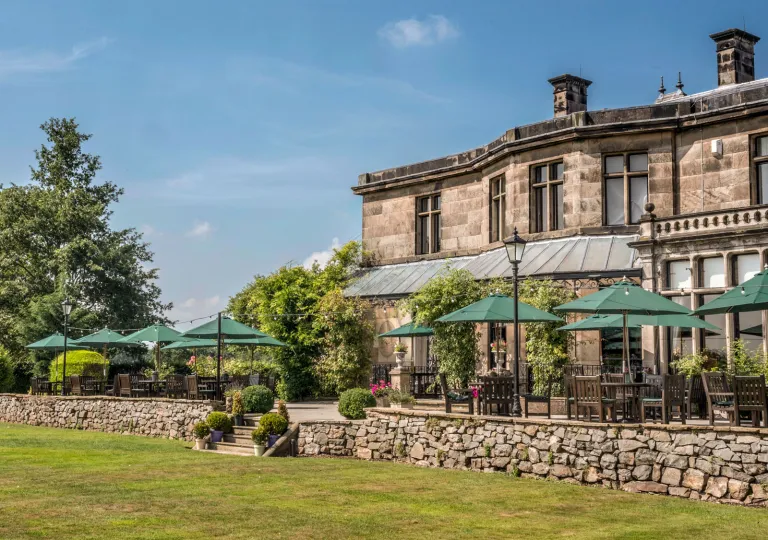 Exterior view of stone building with an outdoor patio with green umbrellas
