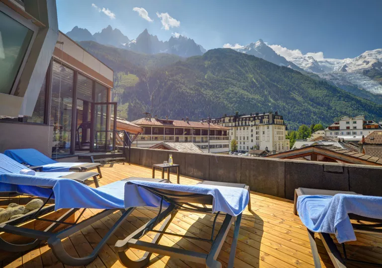 Rooftop patio with reclining chairs looking out towards large mountains