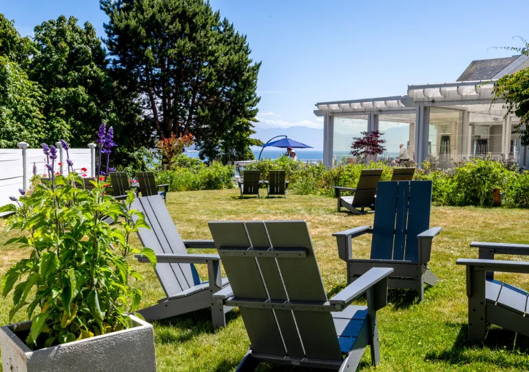 Exterior view of the historic Sooke Harbour House hotel in the Gulf Islands, Canada, featuring its wooden architecture, garden lawn, and surrounding furniture.