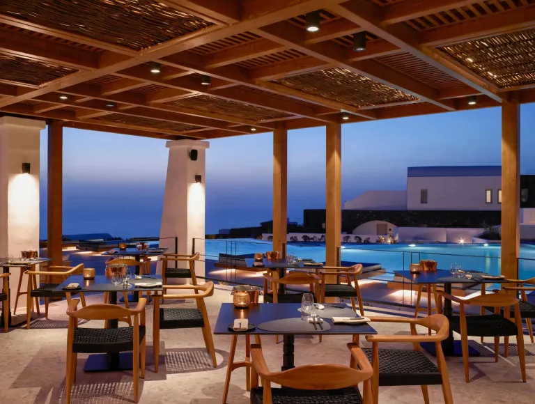 Open air restaraunt with a pool and the ocean in the background.