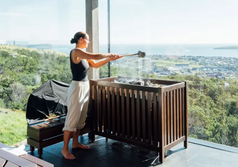 Woman pouring water into a stone sauna