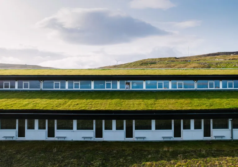 Exterior view of long hotel building with a grass roofing