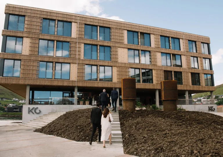 The exterior of the KG Hotel in Klaksvík, Faroe Islands featuring a nature-centric approach and contemporary architecture with extensive wood paneling.