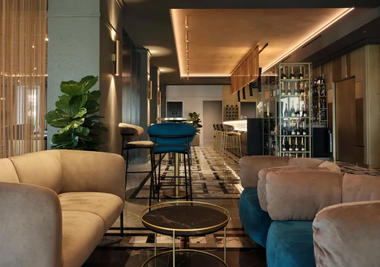 The Boutique Hotel Stresa lobby lounge with a modern, deep blue and green velvet seating, polished brass accents, and mirrored surfaces.