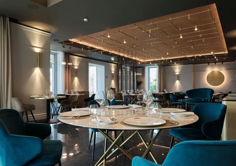 The restaurant at the Boutique Hotel Stresa in Stresa, Italy, featuring modern lighting, dark flooring, and bright blue armchairs.