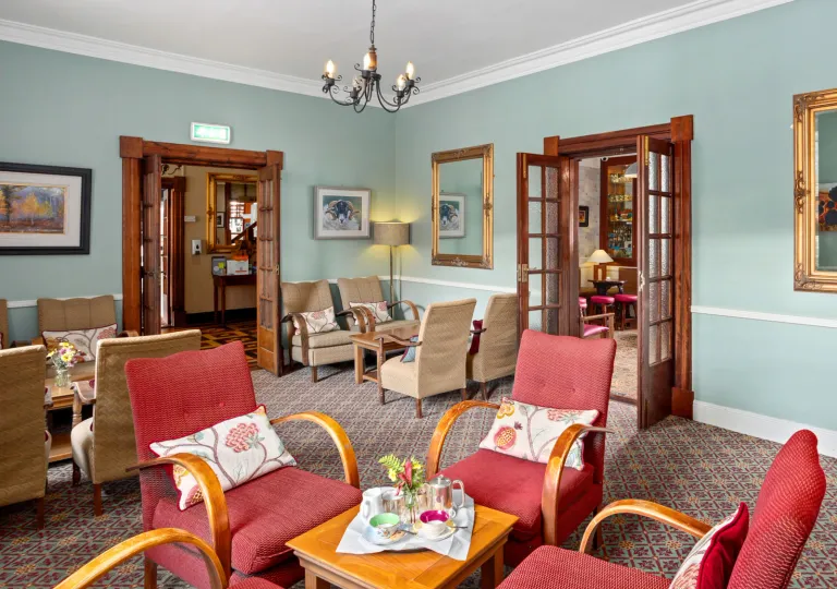 Seating and lounge area with red and beige, cushioned chairs surrounding coffee tables