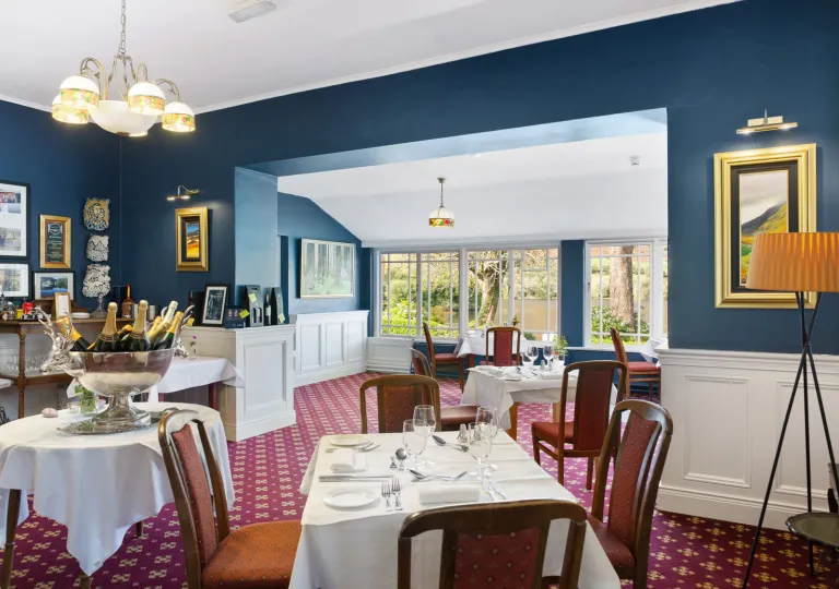 Restaurant dining hall with white tables and cushioned, red chairs in a blue room