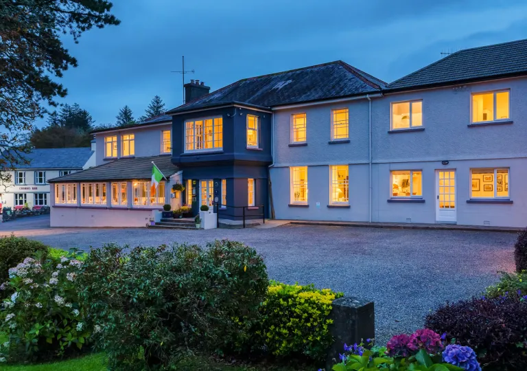 Evening, exterior view of a large white and gray building with a garden in front