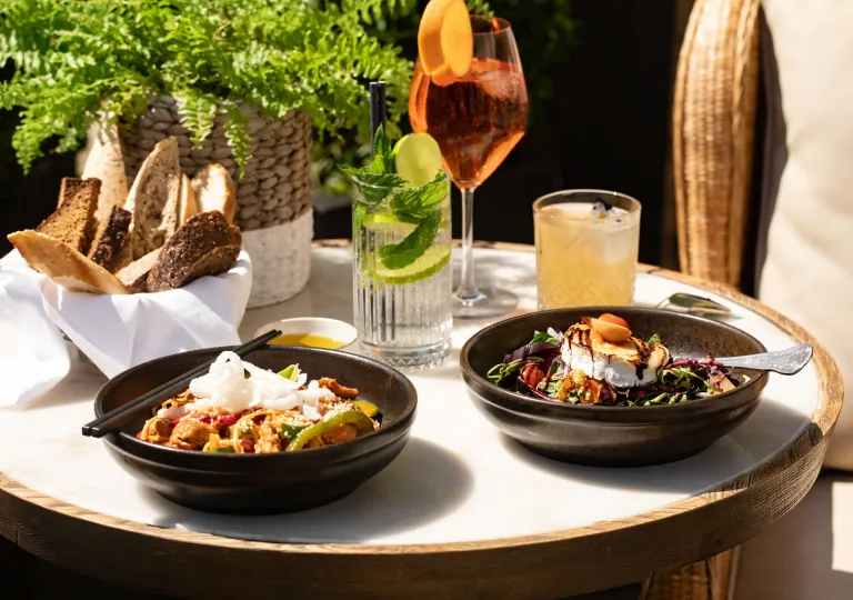 Circular, white dining table with two bowls of food and two glasses of drinks