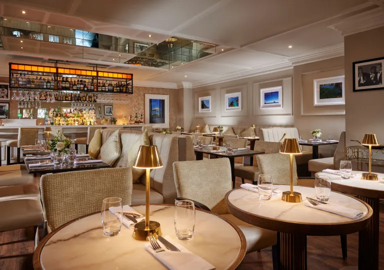 Restaurant with circular tables and beige, cushioned chairs