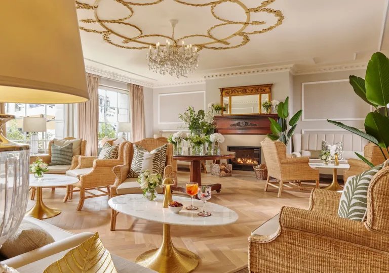 Lounge area in front of a fireplace, with circular tables and woven chairs