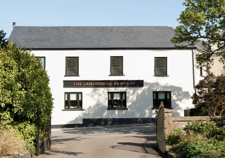 Exterior view of white and gray building with trimmed bushes in front