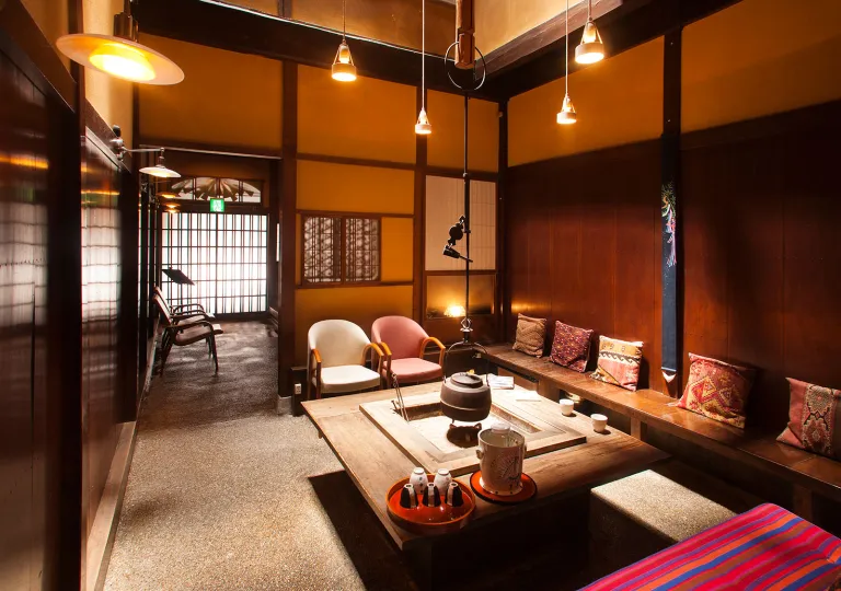 Japanese-style room with a table in the center and wooden benches surrounding the perimeter of the room