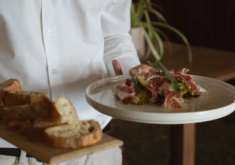Restaurant staff holding two plates of food and bread