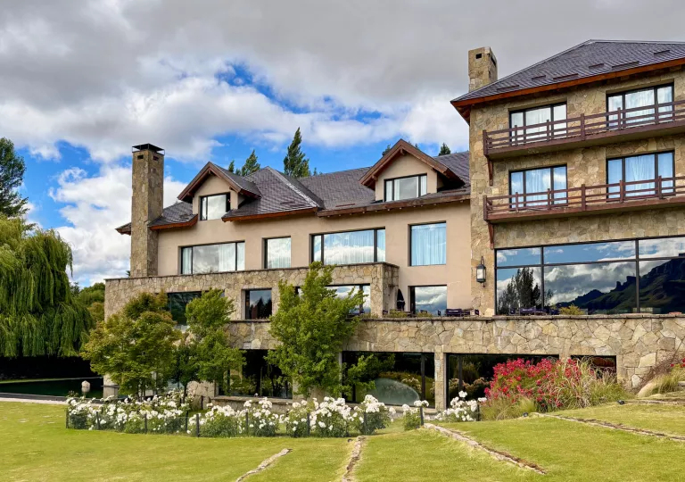 Exterior view of gray hotel building with large windows and a grass field in front