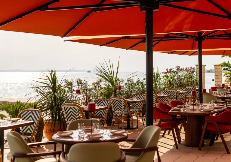 Outdoor patio with dining tables and large, red umbrellas