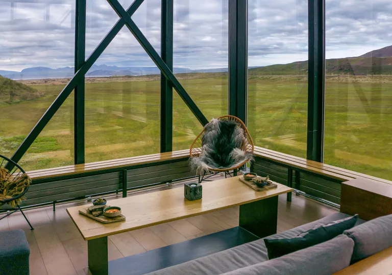 Gray couch with wooden table in the corner of a room with large windows