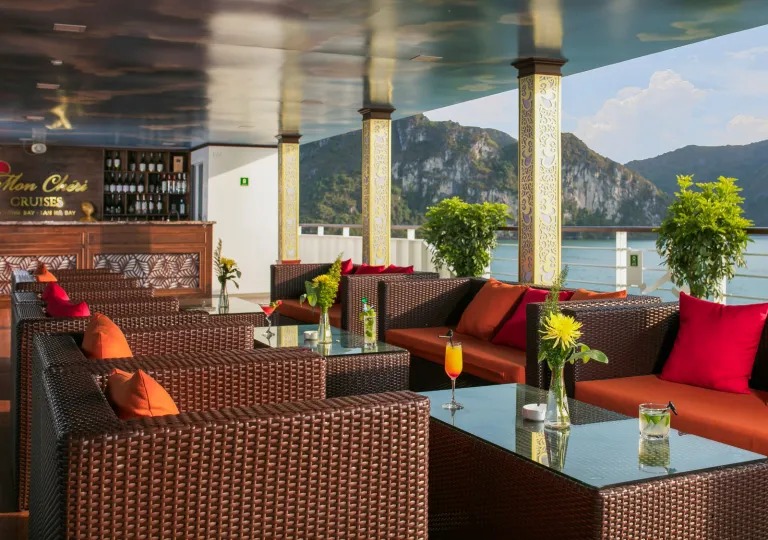 Outdoor patio  with woven, cushioned chairs with views of the ocean in the background