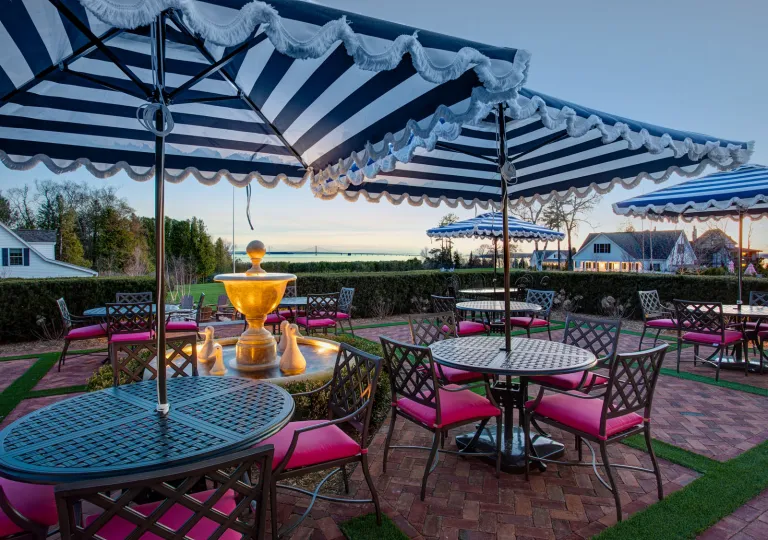 Outdoor patio with multiple circular tables and chairs, and striped white and black umbrellas