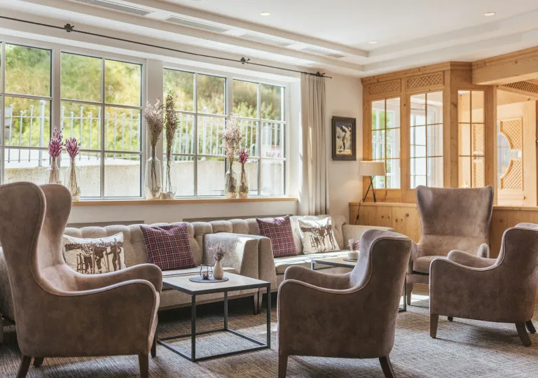 Seating area and lounge with beige, cushioned chairs and large windows