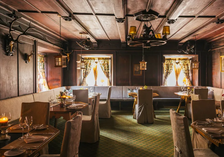Dimly lit restaurant dining area with cushioned chairs and large dining tables