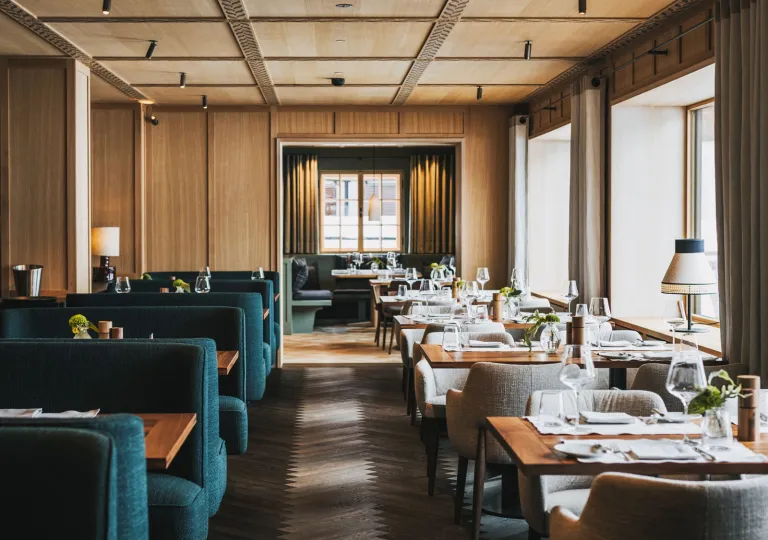 Restaurant dining area with blue, cushioned sofas and large windows
