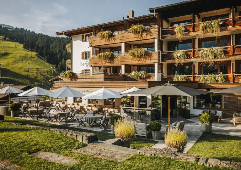 Exterior view of brown hotel building with balconies and a grass lawn in front