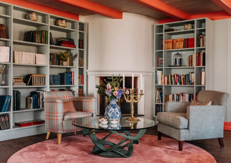 Library and lounge area with cushioned sofas in front of book shelves