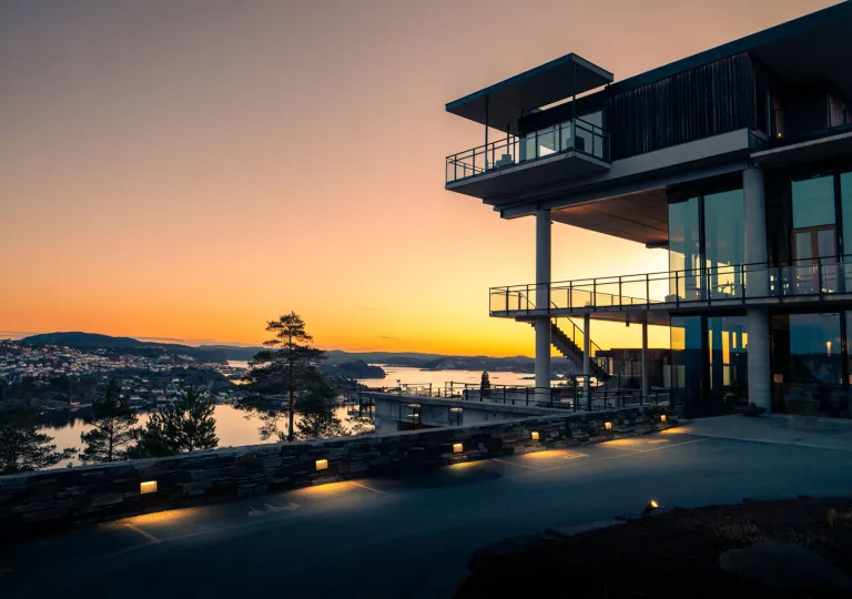 Sunset view of a large building with glass balconies looking out to a lake