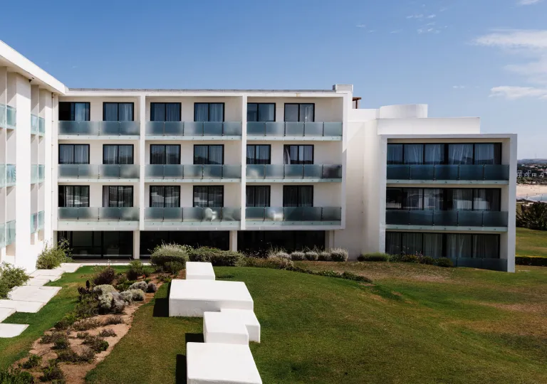 The exterior of the Memmo Baleeira Hotel in Sagres, Portugal, featuring white walls and glass-railed balconies.