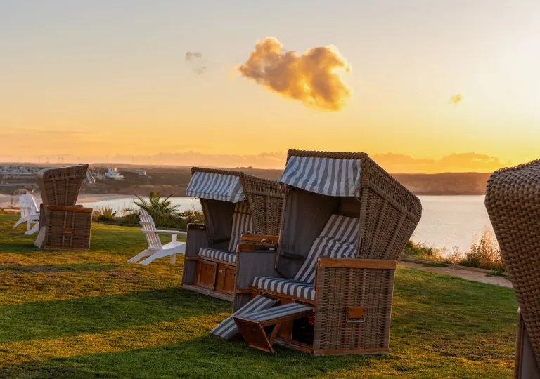 Beach chairs at Memmo Baleeira Hotel in Sagres, Portugal features a reclining wicker design with striped cushions.