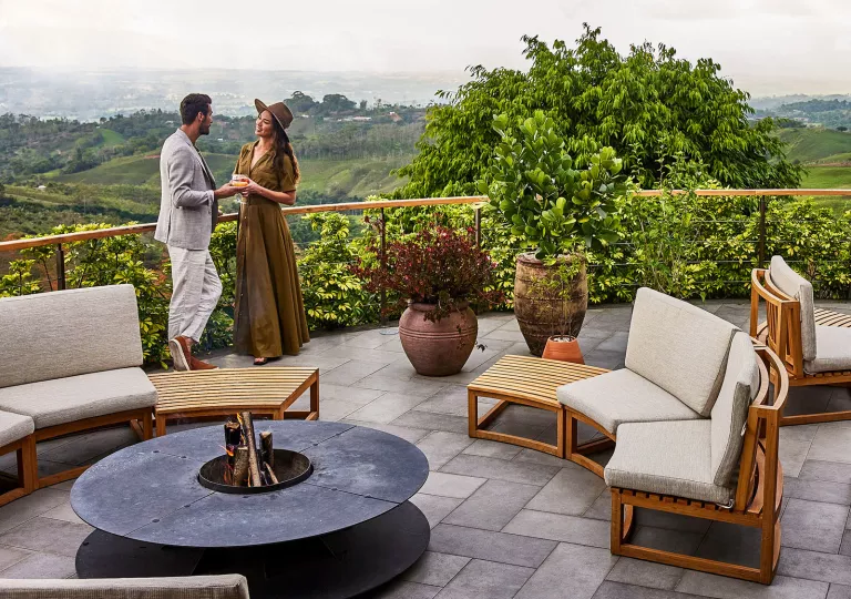 Man and woman standing on a rooftop balcony with cushioned chairs