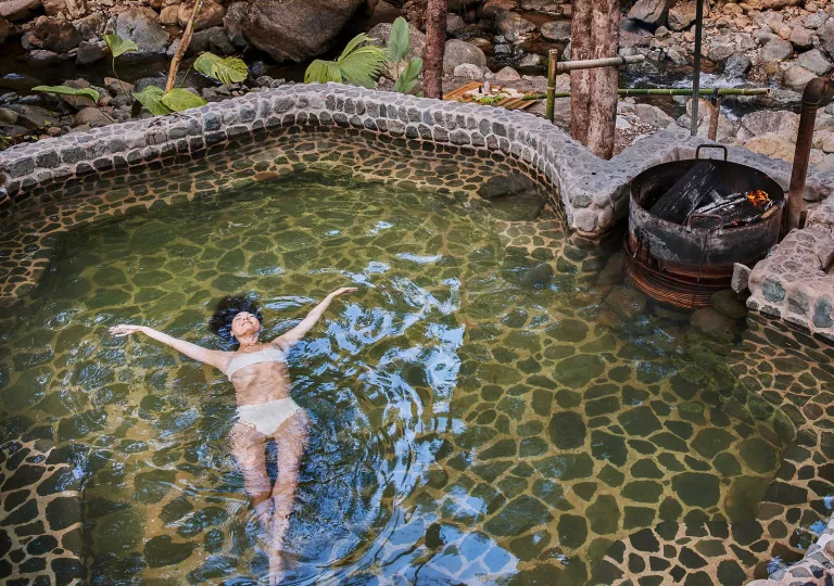 Woman in a pool with her arms wide open