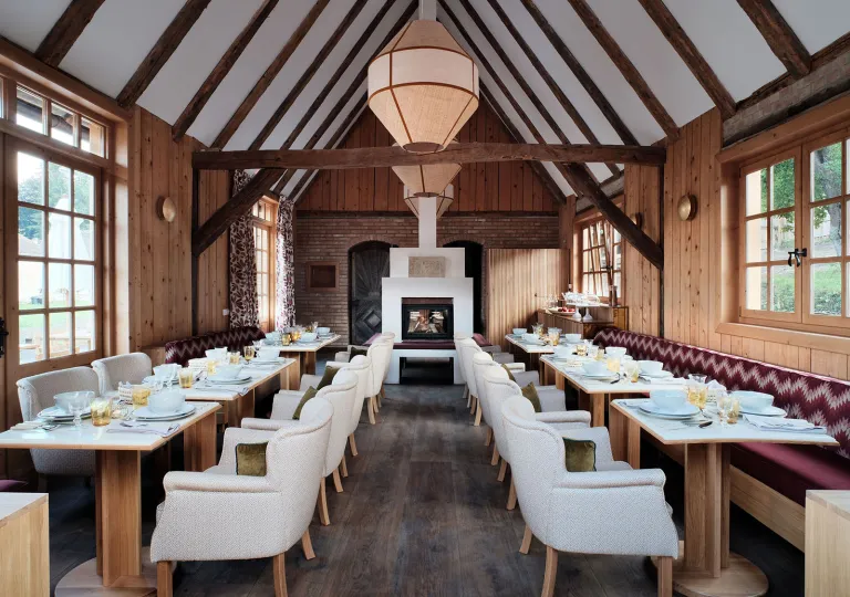 Restaurant with white, cushioned chairs surrounding wooden dining tables