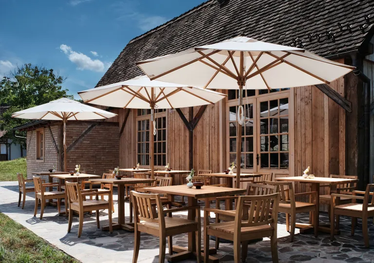 Outdoor patio and dining area, with wooden chairs and tables under white umbrellas