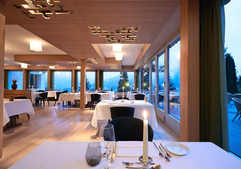 Restaurant dining area with white cloths and candles over square tables
