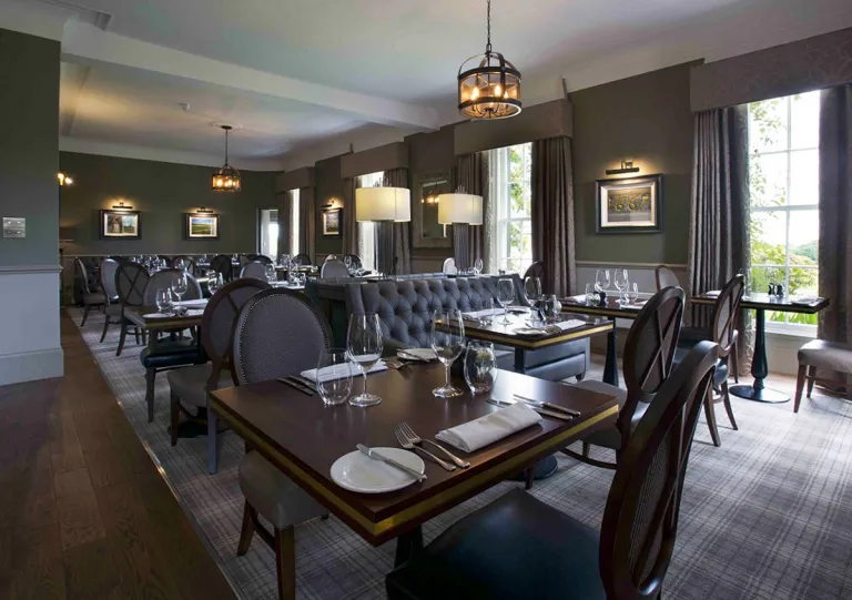 Restaurant with dark wooden tables and black chairs, with tall windows along the walls