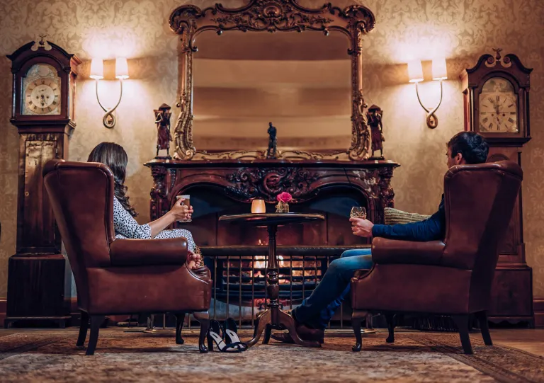 Man and women sitting on leather chairs in front of a fireplace