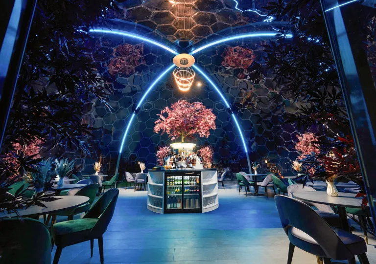 Large dome-shaped restaurant with plants and neon lights