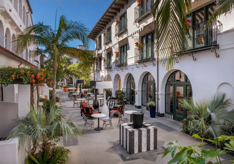 The outdoor courtyard of the Hotel Californian in Santa Barbara, featuring Spanish arched architecture and palm trees.