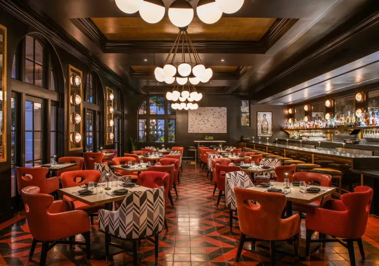 The restaurant Hotel Californian in Santa Barbara, features red and black tiled floors, red chairs and chandeliers.