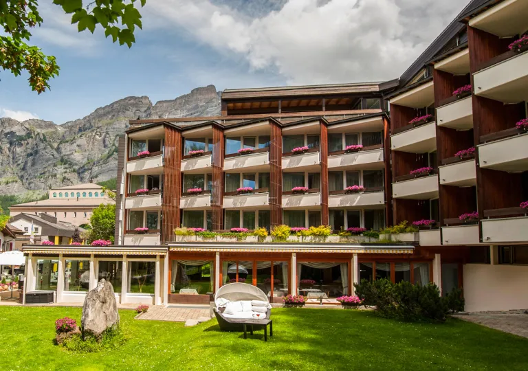 Exterior view of white and brown, multi-level hotel building with a grass lawn in front