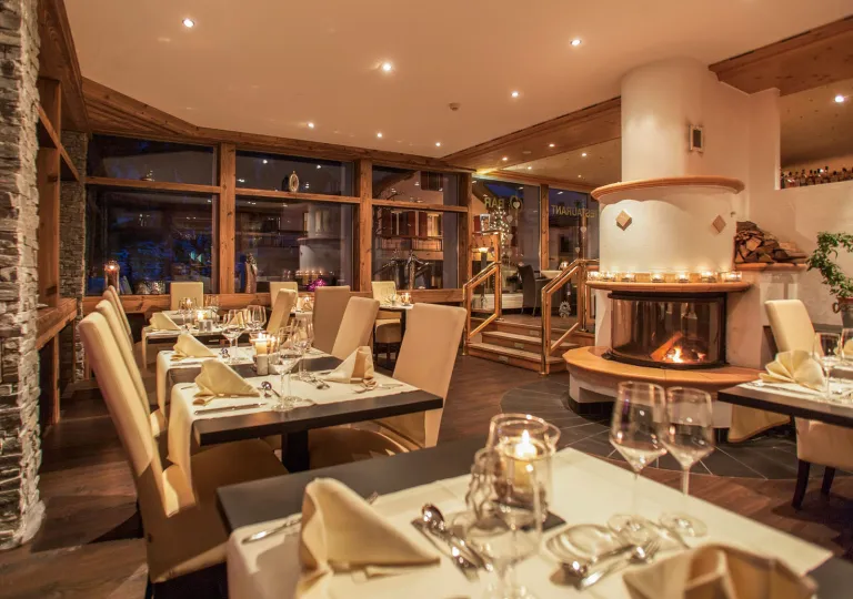 Restaurant dining area with white brown tables and beige chairs, with a fireplace in the background
