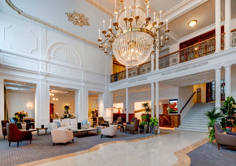 The grand, high-ceilinged interior with a multi-tiered crystal chandelier in the lobby of Grand Hotel des Bains Kempinski in St. Moritz, Switzerland.