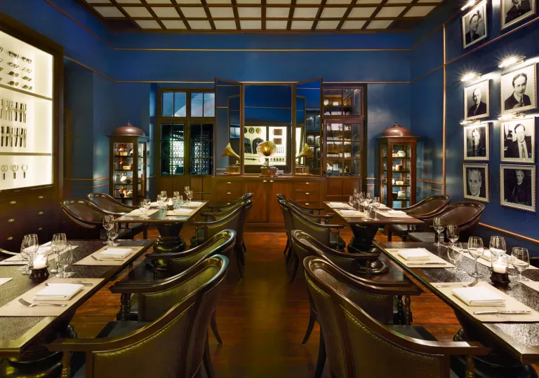 Restaurant dining area with dark, wooden chairs and rectangle tables in a blue room