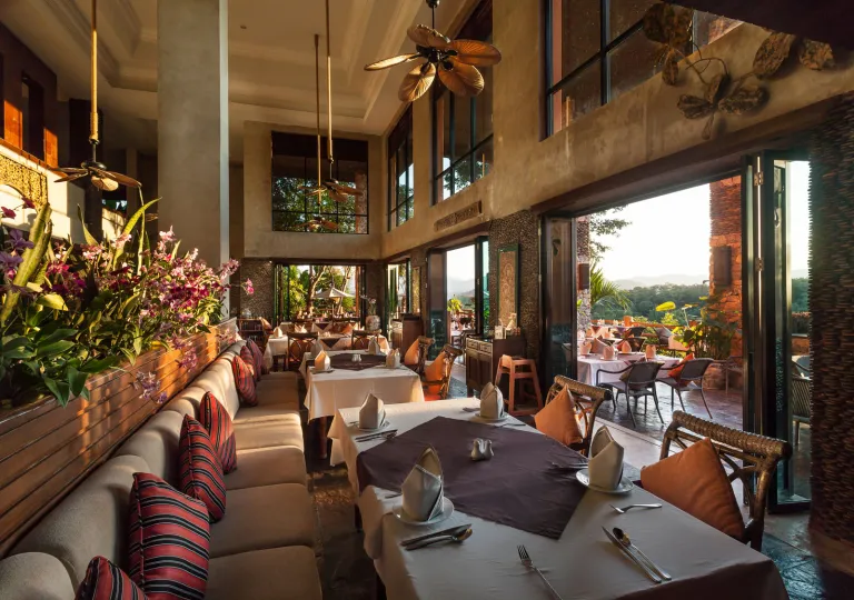 Restaurant with cushioned sofas and white dining tables, with large windows to the right
